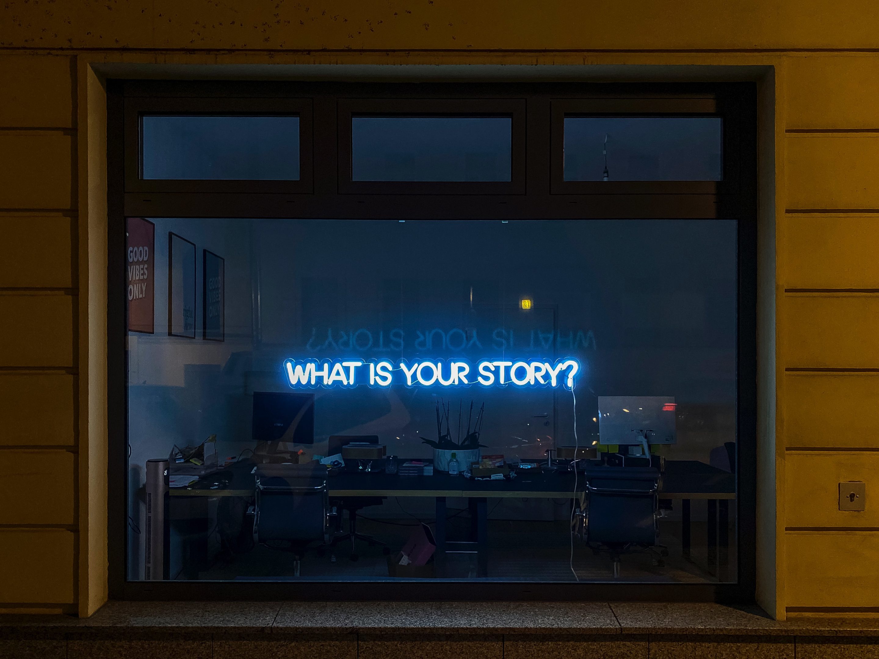 Blue neon sign that says "what is your story?"